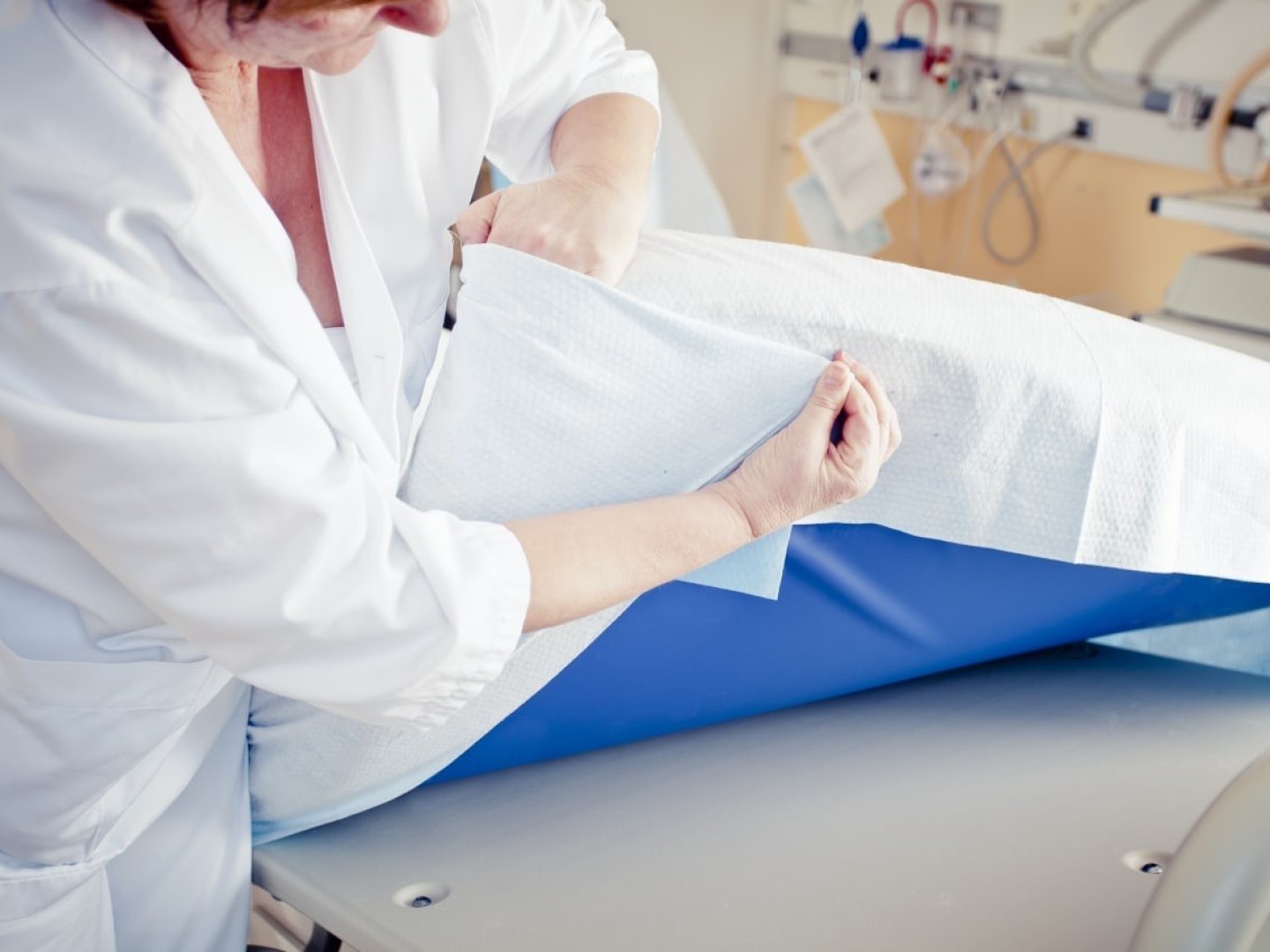 Bilde av en sykepleier som legger på et spesielt laken på en sykehusseng. 