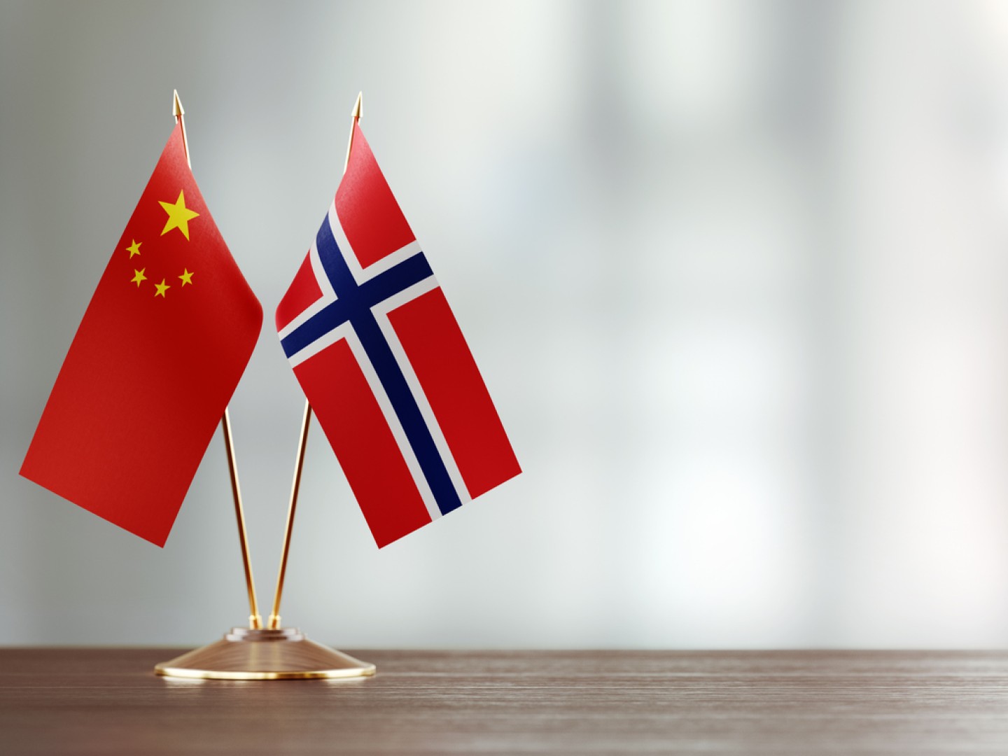 Norsk og kinesisk flagg i stativ sammen på et bord