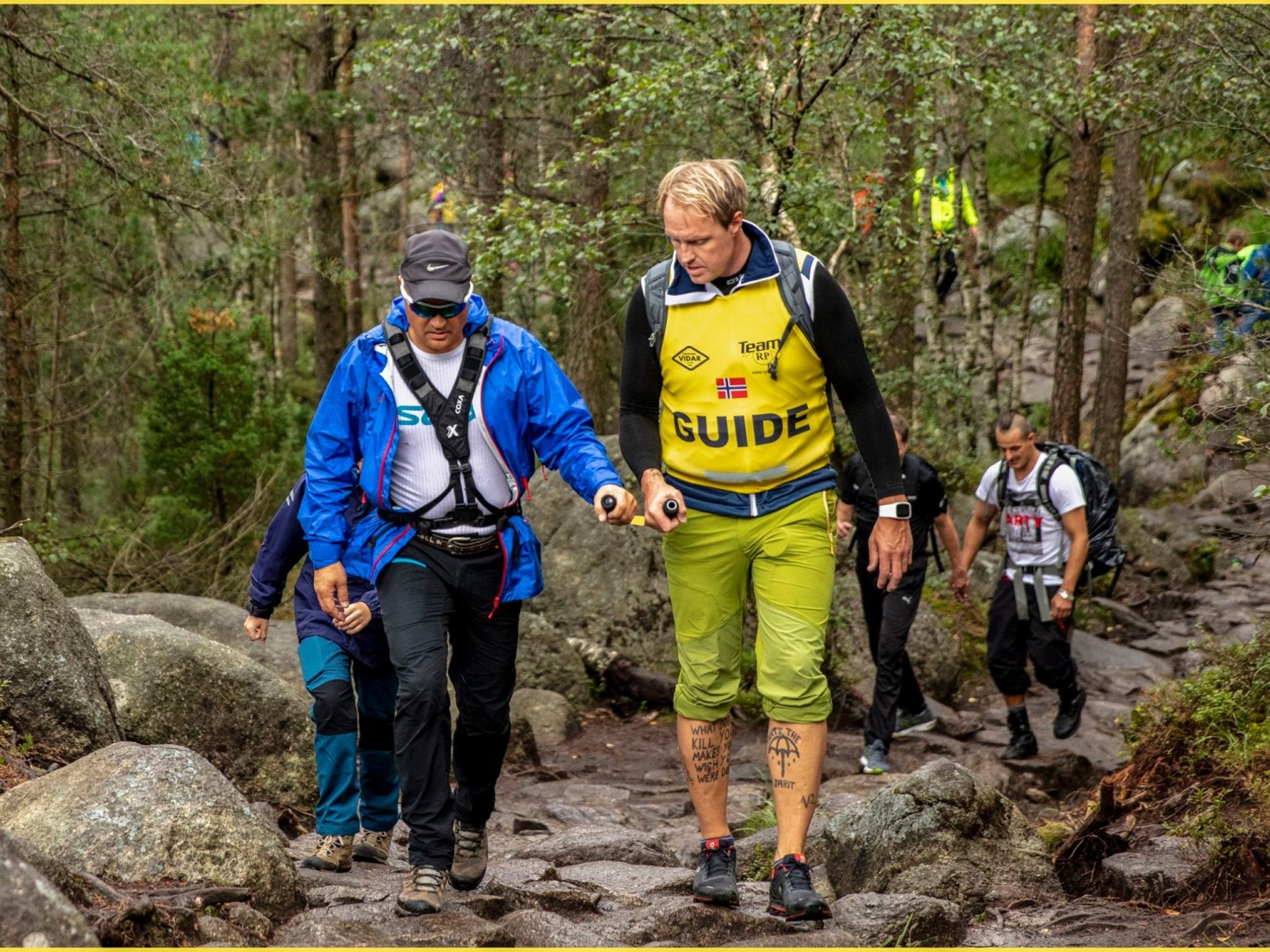 Ledsagerbøyle fra U-GO brukes av to menn på tur i skogen.