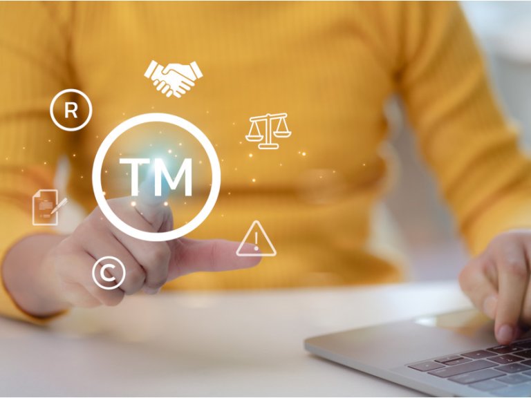 Person peker på symbolene for trademark (bokstavene TM med sirkel rundt), registrert varemerke (bokstaven R med sirkel rundt) og opphavsrett (bokstaven C med sirkel rundt).
