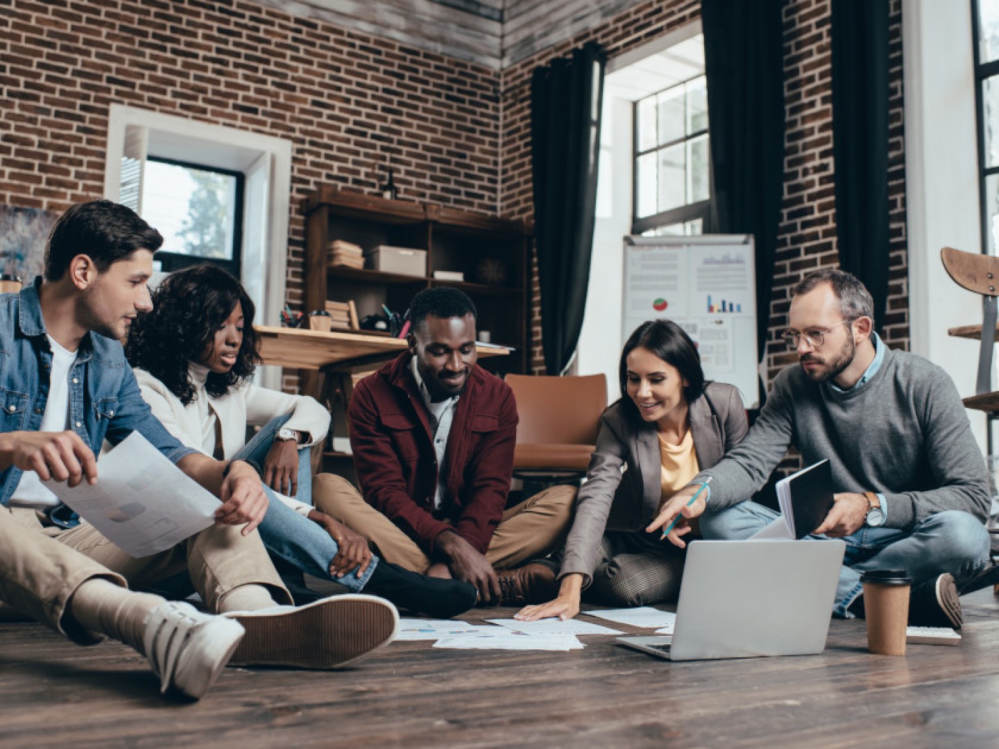 Gruppe med mennesker sitter på gulvet og planlegger.