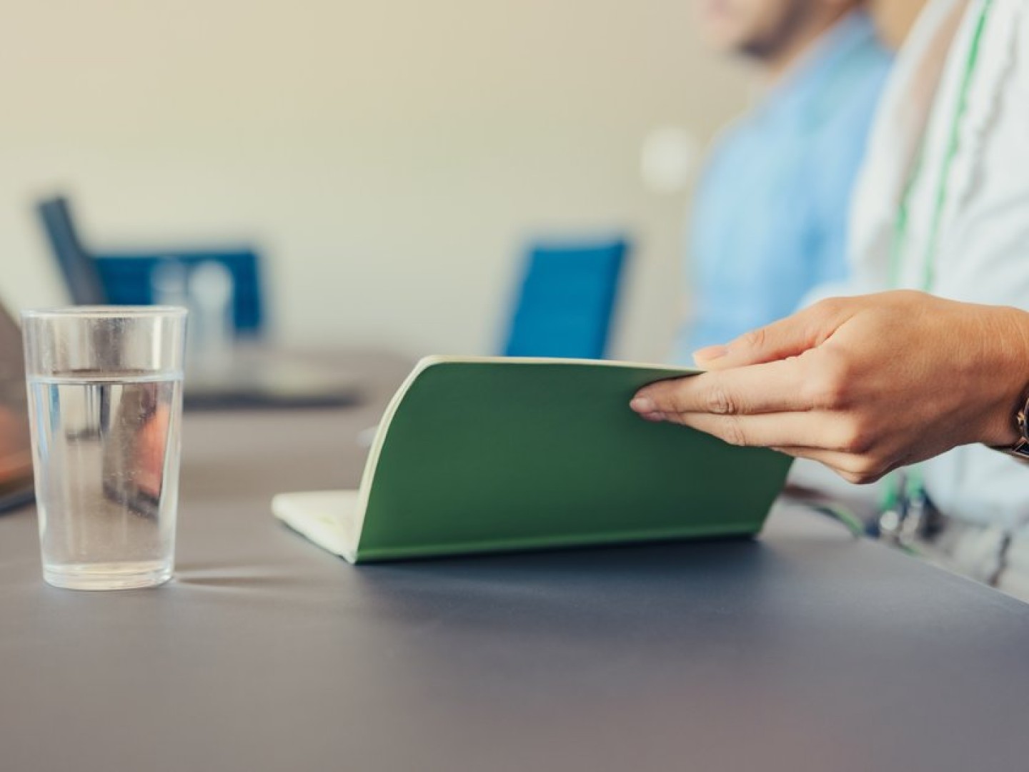 Hand opening a notebook in a meeting room