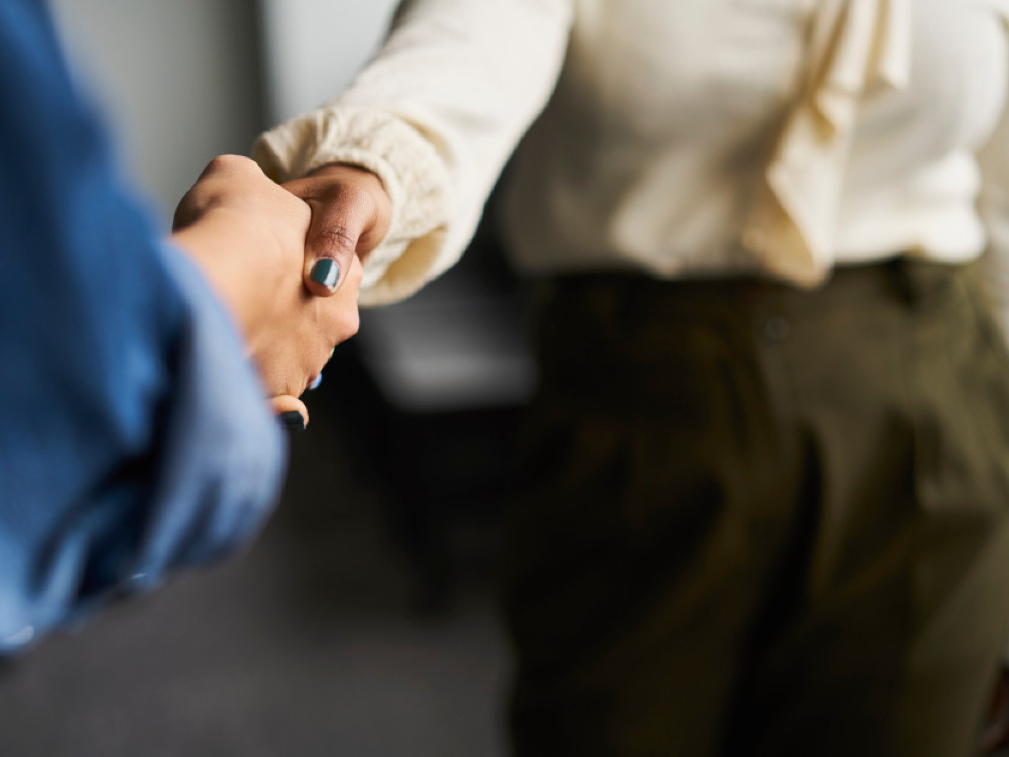 Two people shaking hands across the table.
