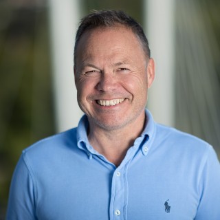 Nærbilde av smilende mann i blå skjorte