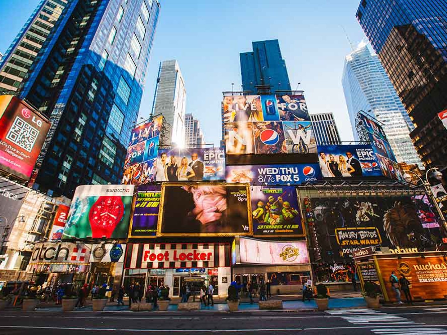 Many advertising signs with logos in a street environment with skyscrapers.