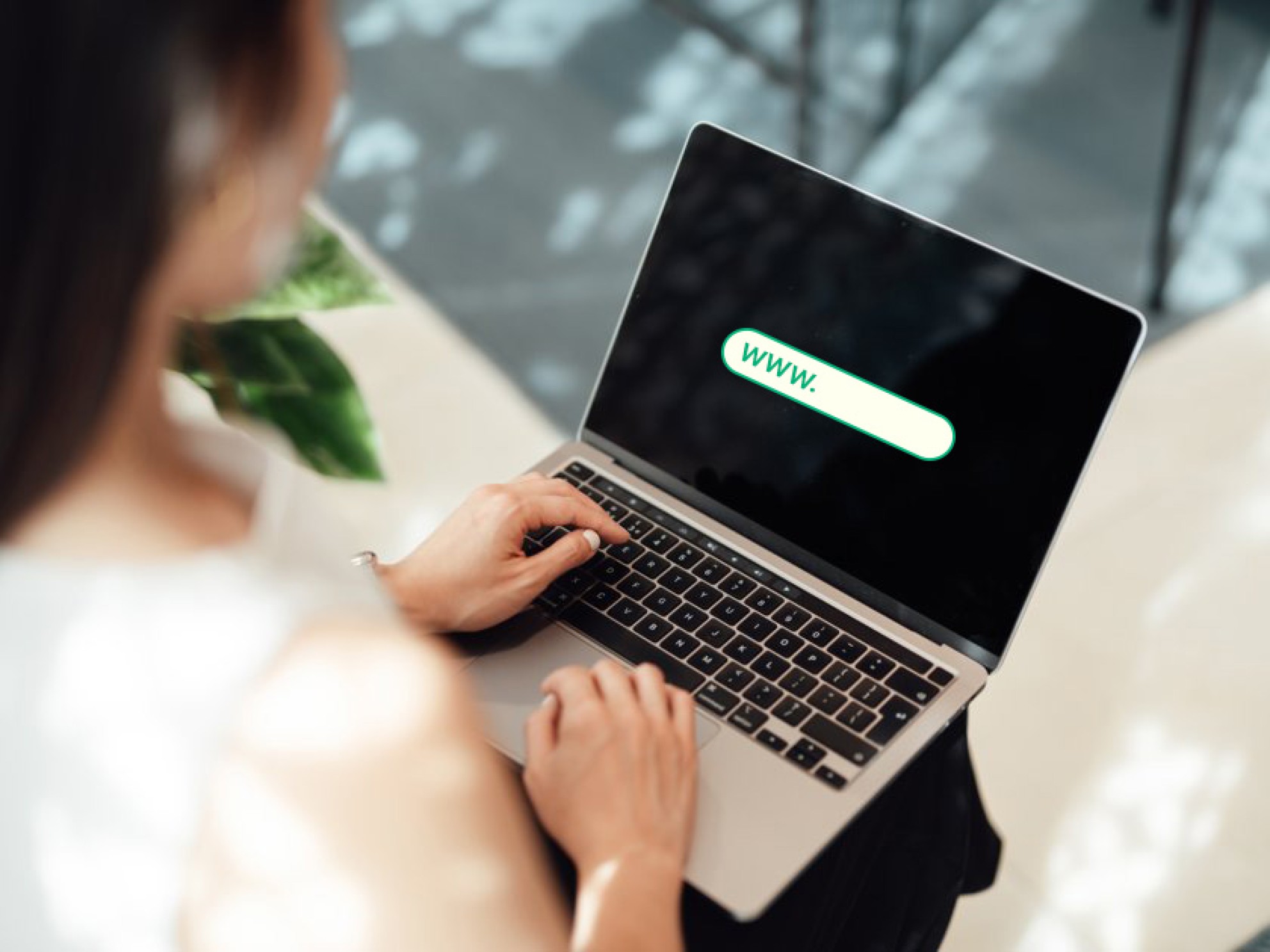 Woman typing the beginning of a domain name on a laptop