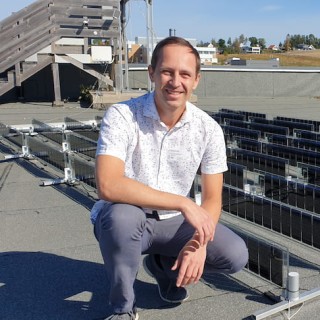 Trygve Mongstad sitter på huk foran et solcellepanel