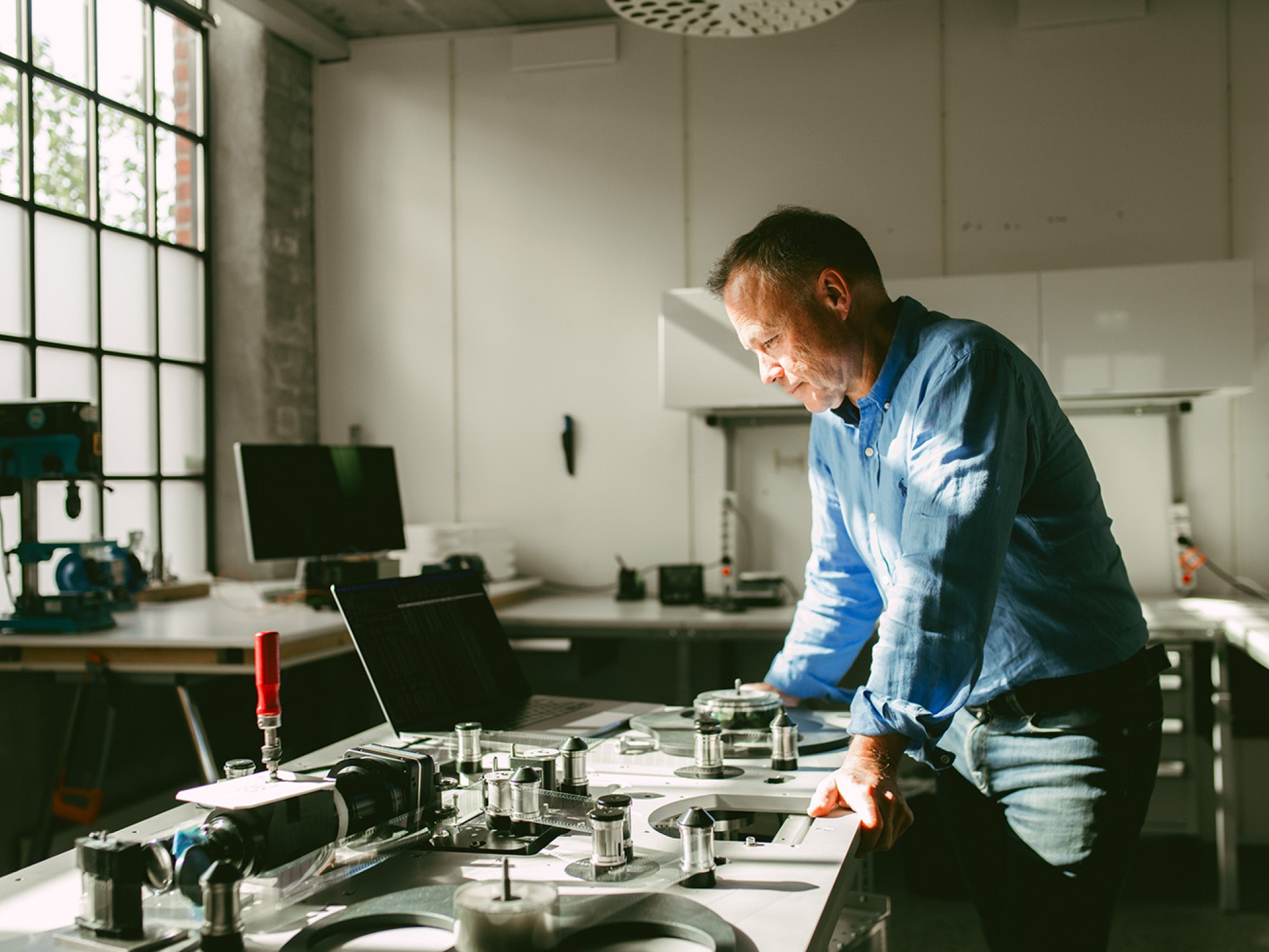 Rune Bjerkestrand står ved arbeidsbenk med teknisk utstyr.