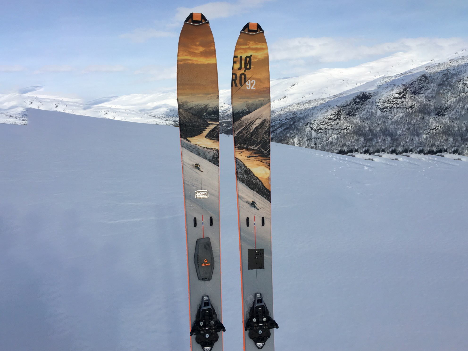 Bilde av et par fjellski med en elektronisk dings og fjell og snø i bakgrunnen