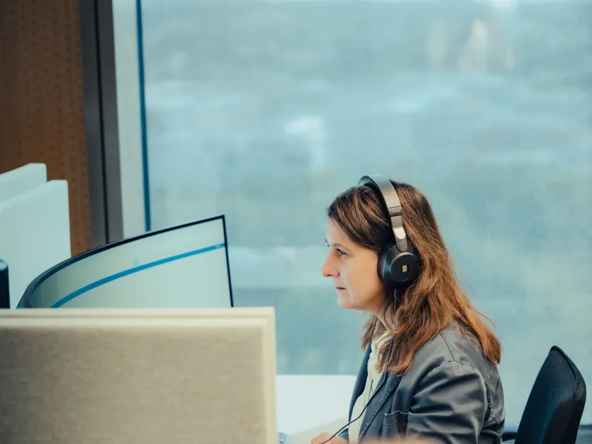 Kvinner sitter med høretelefoner foran en skjerm